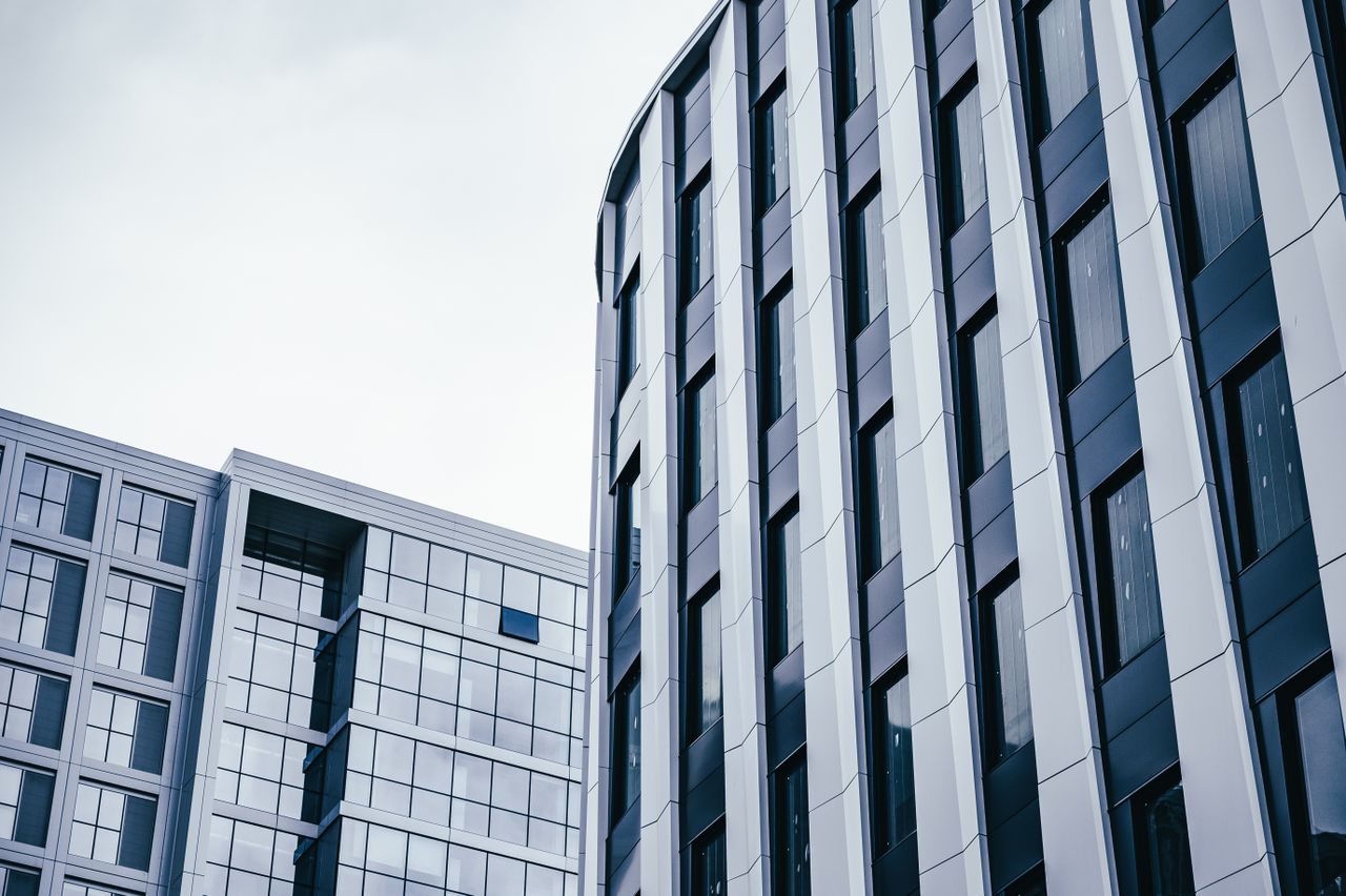 Contemporary office buildings with glass facades under a cloudy sky, showcasing modern urban architecture
